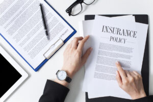 Person reviewing an insurance policy document, emphasizing Personal Injury Protection (PIP) coverage details, with a pen and glasses on a desk.