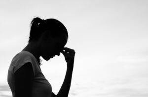 Silhouette of a woman holding her forehead, conveying emotional distress related to loss and personal injury claims.