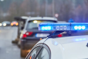 Police vehicle with flashing blue lights responding to an accident scene involving a car, emphasizing the legal implications of equipment-related car accidents in Portland, OR.