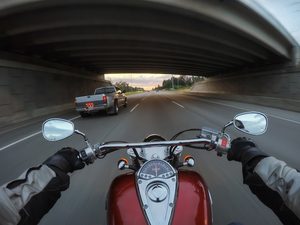 Motorcyclist lane splitting between cars on a Portland freeway